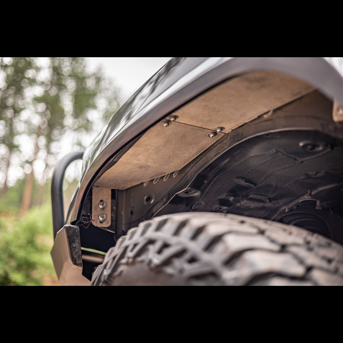 View up under the driver's side fender showing the aluminum fender liners included with the C4 High Clearance Fender Liner kit.