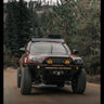 Rolling photo of a 4th Gen 4Runner driving at speed down a mountain road, equipped with a Sherpa roof rack, 35" tires and a C4 Fabrications Overland winch bumper. 