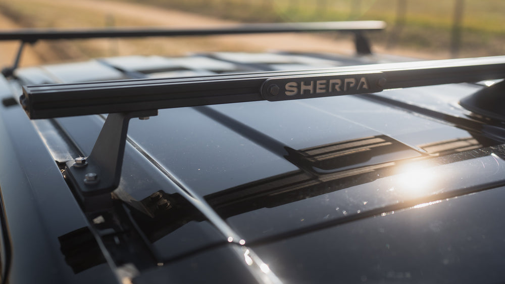 Car roof rack with Sherpa branding on a vehicle in an outdoor setting.