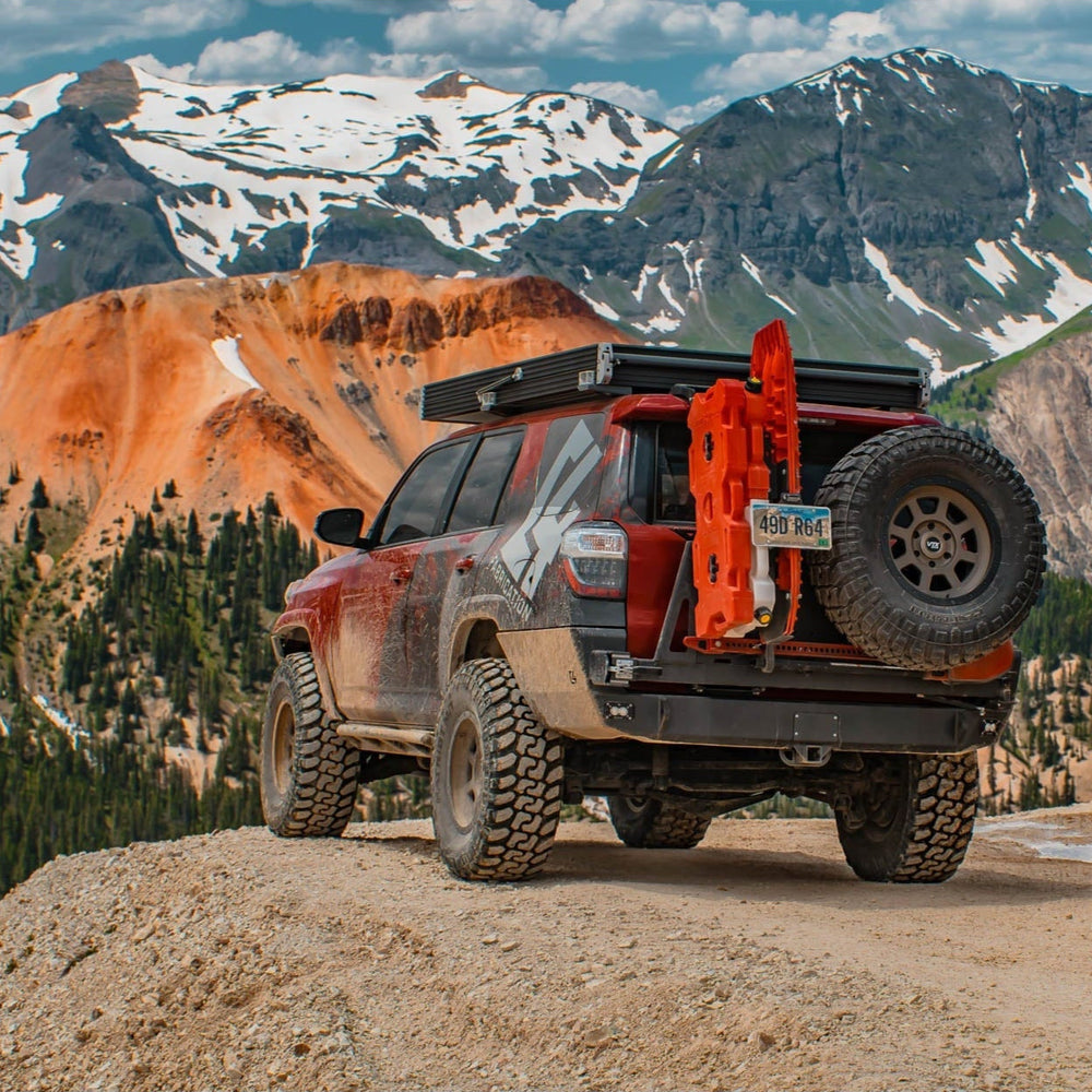 Maroon 4Runner at a mountain overlook with a rooftop tent, sliders and the Overland Rear Bumper with full-width single swing from C4 Fabrications.