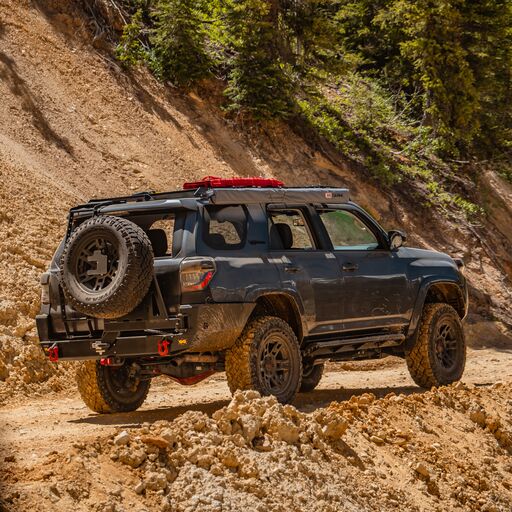 4Runner on a dirt trail in the mountains equipped with an awning, roof rack and the C4 Overland Rear Bumper.