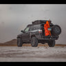 Black 4Runner on a beach equipped with the C4 fabricated steel rear bumper with dual swing-outs holding a spare tire on the passenger side and RotoPax, MaxTrax and a high-lift jack on the driver's side.
