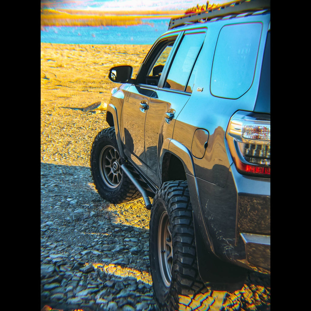 Look down the side of a grey 4Runner overlooking a lake, showing the kick-out at the rear of the C4 Rock Sliders.