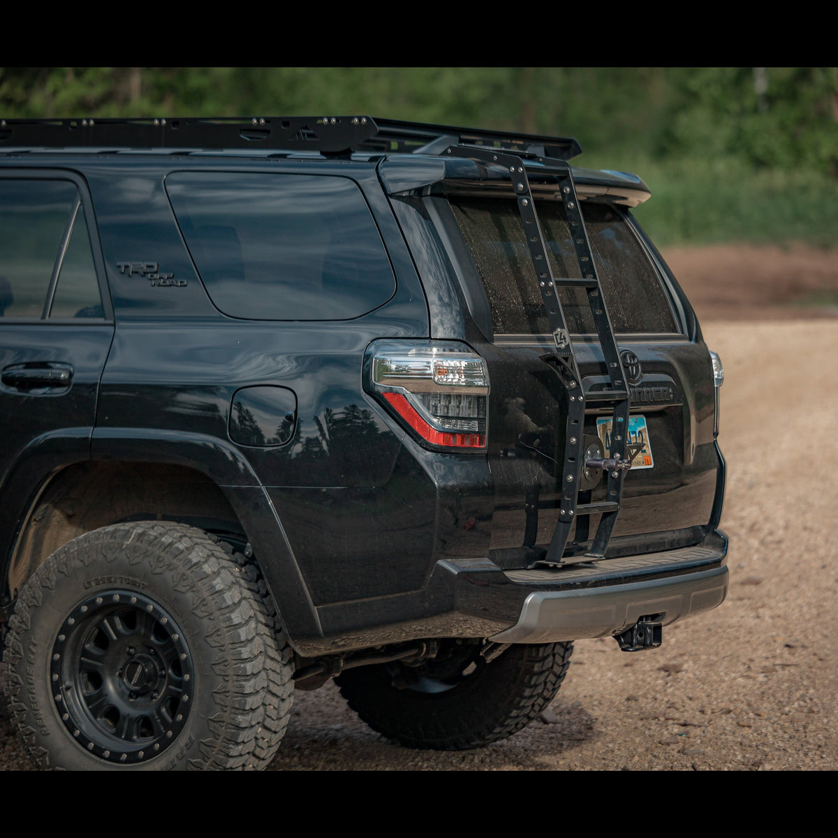 Driver's rear quartering shot showing a black 4Runner with the C4 Summit hatch ladder. 