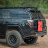 Quartering side rear angle of a black 4Runner with the C4 hatch ladder and a single RotopaX mounted to it.