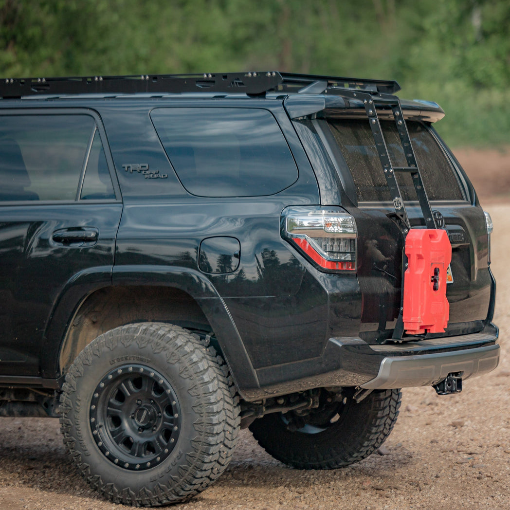 Quartering side rear angle of a black 4Runner with the C4 hatch ladder and a single RotopaX mounted to it.
