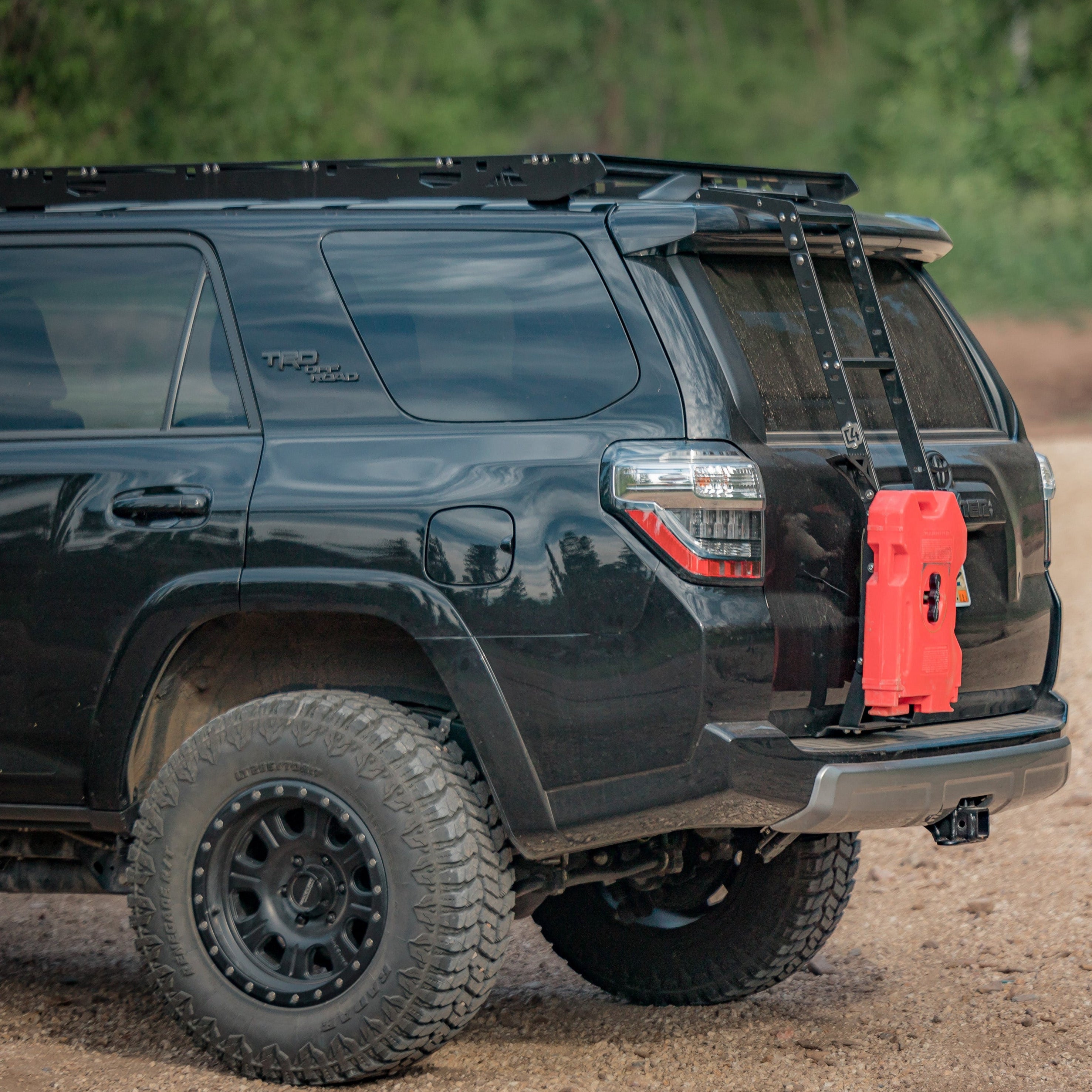 Quartering side rear angle of a black 4Runner with the C4 hatch ladder and a single RotopaX mounted to it.