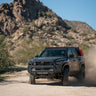 Off-road 4Runner driving on a dirt road with mountains in the background, equipped with 6th Gen 4Runner Roof Rack