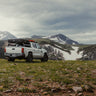 Well-equipped white Tacoma in a mountain meadow with a C4 Overland rear bumper installed.