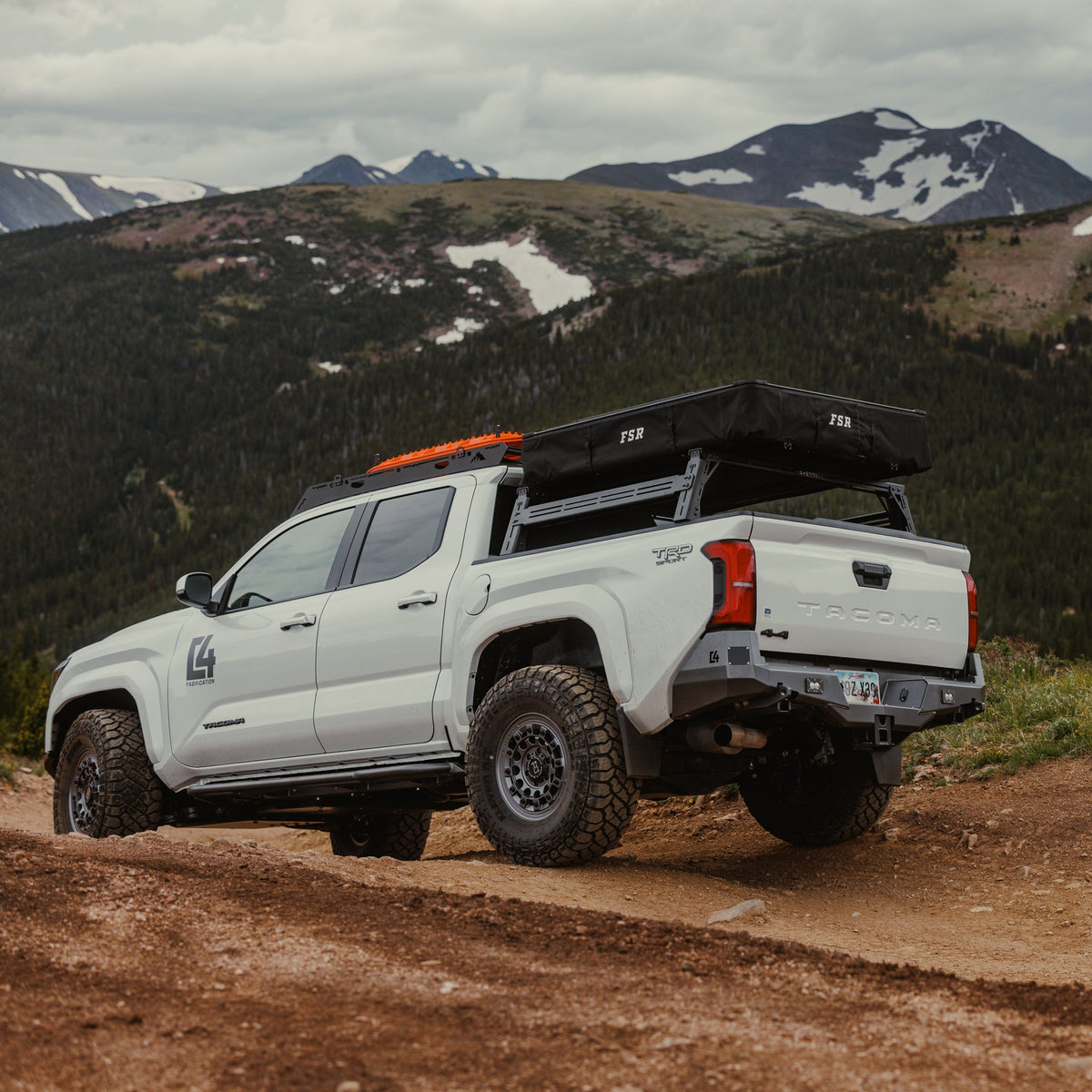 Rear view of a white Tacoma exploring the mountains and well-equipped with overlanding gear and accessories.