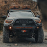 Grey Tacoma on a mountain road with a winch bumper.