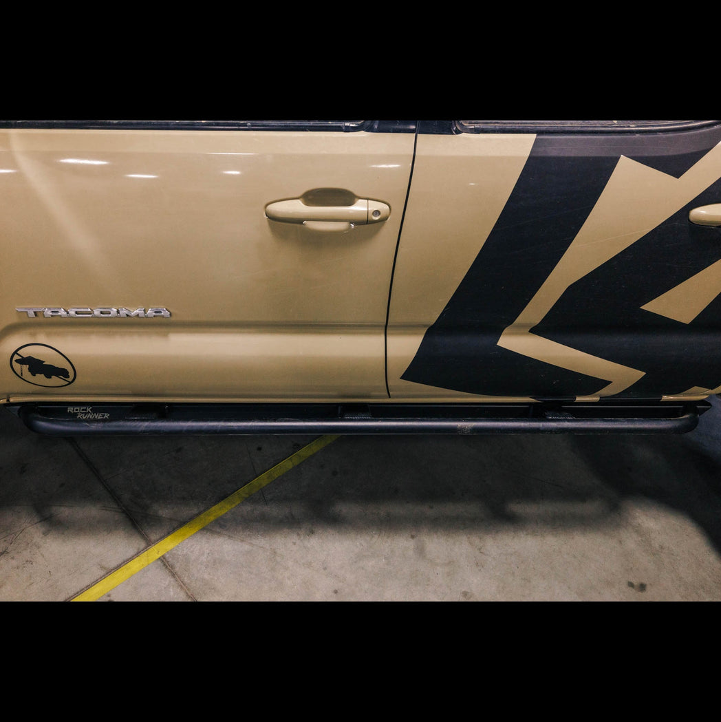 Side view of the C4 Fabrication Rock Runner Sliders for the 3rd Generation Tacoma installed on a tan 4-door example. 