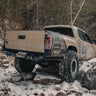 Tan Tacoma rock crawling in the snow and showing off the C4 Rock Runner rear bumper and its extreme departure angle.