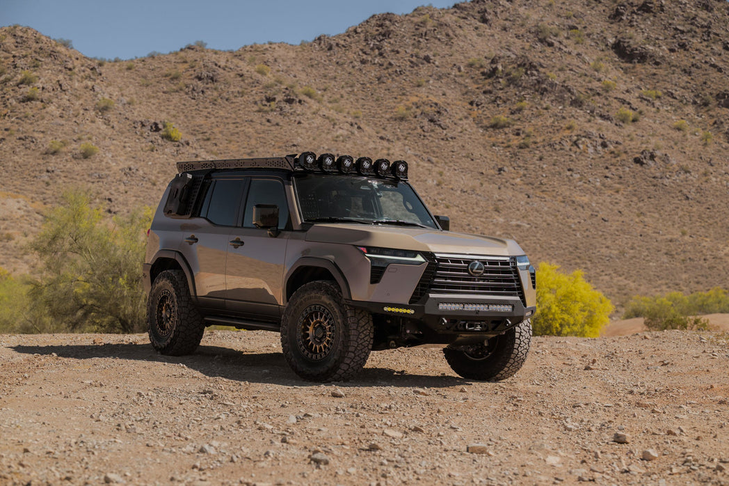 Off-road GX 550 fully equipped with off road bumpers, roof rack, light brackets, and molle panels in a desert landscape with mountains in the background