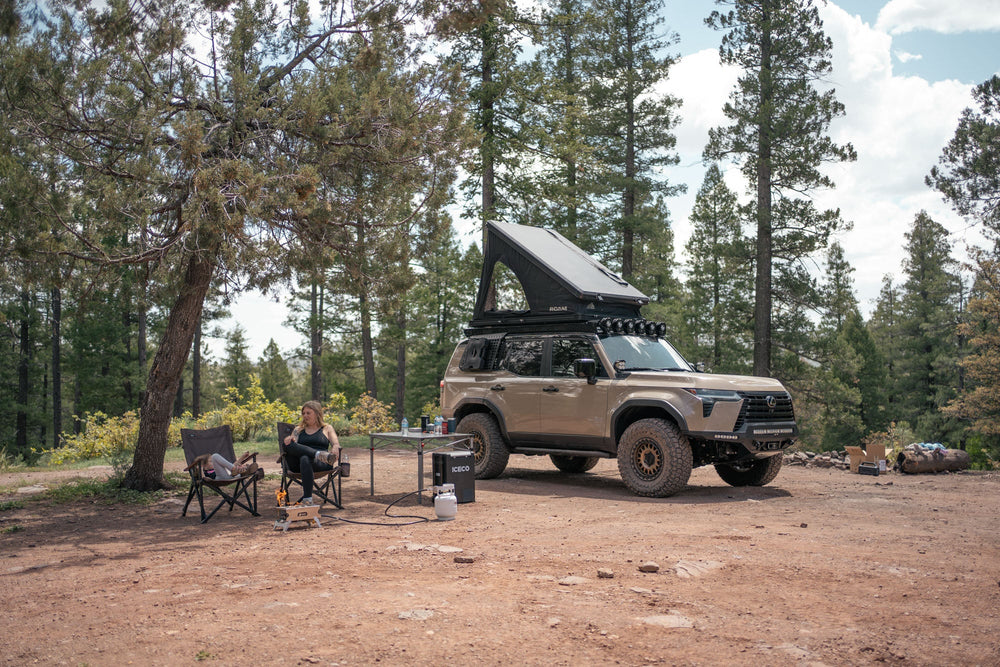 Camp setup with the GX 550 fully equipped. The SUV is equipped with off road bumpers, roof rack, tent, light brackets, and molle panels from Rago Fabrication.