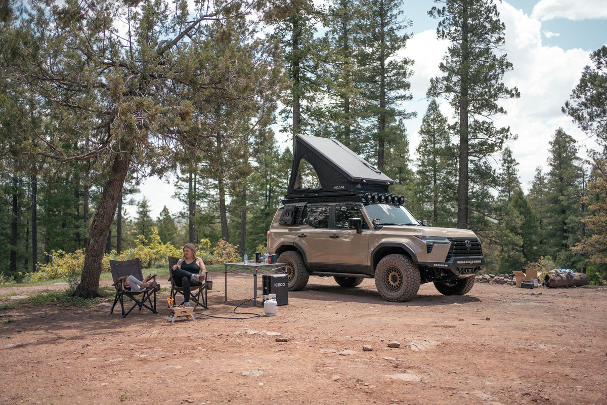 Camp setup with the GX 550 fully equipped. The SUV is equipped with off road bumpers, roof rack, tent, light brackets, and molle panels from Rago Fabrication.