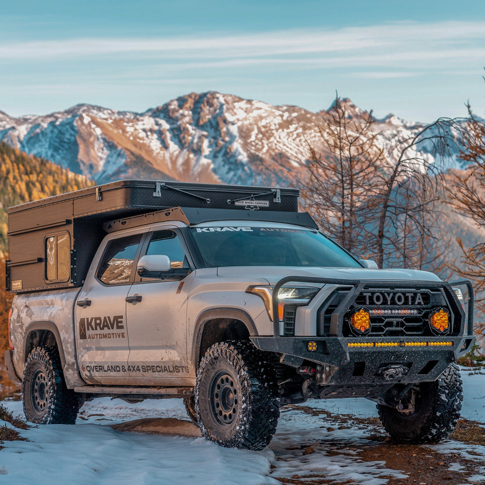 White CrewMax Tundra parked in the mountains with overland bumper and Four Wheel Camper.