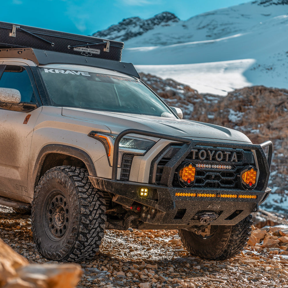 Close-up quartering view of the C4 Overland bumper for the 3rd Generation Toyota Tundra with lighting installed and the full-height bull bar option with headlight hoops. 