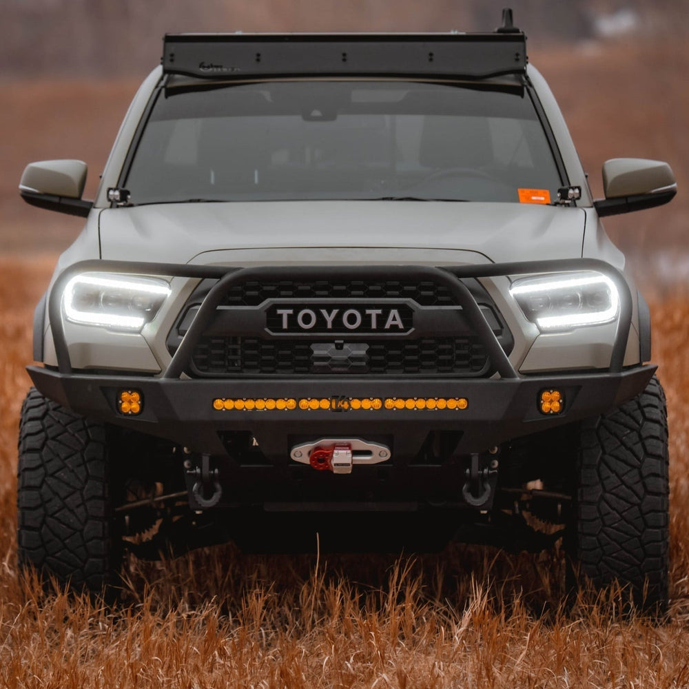 Straight on view of a Tan Tacoma with a roof rack and C4 Overland front winch bumper.
