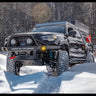 Black four-door Tacoma wheeling in the snow with an Overland winch bumper.