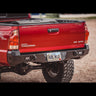 Rear view of the C4 Overland rear bumper on a red 2005+ Tacoma.