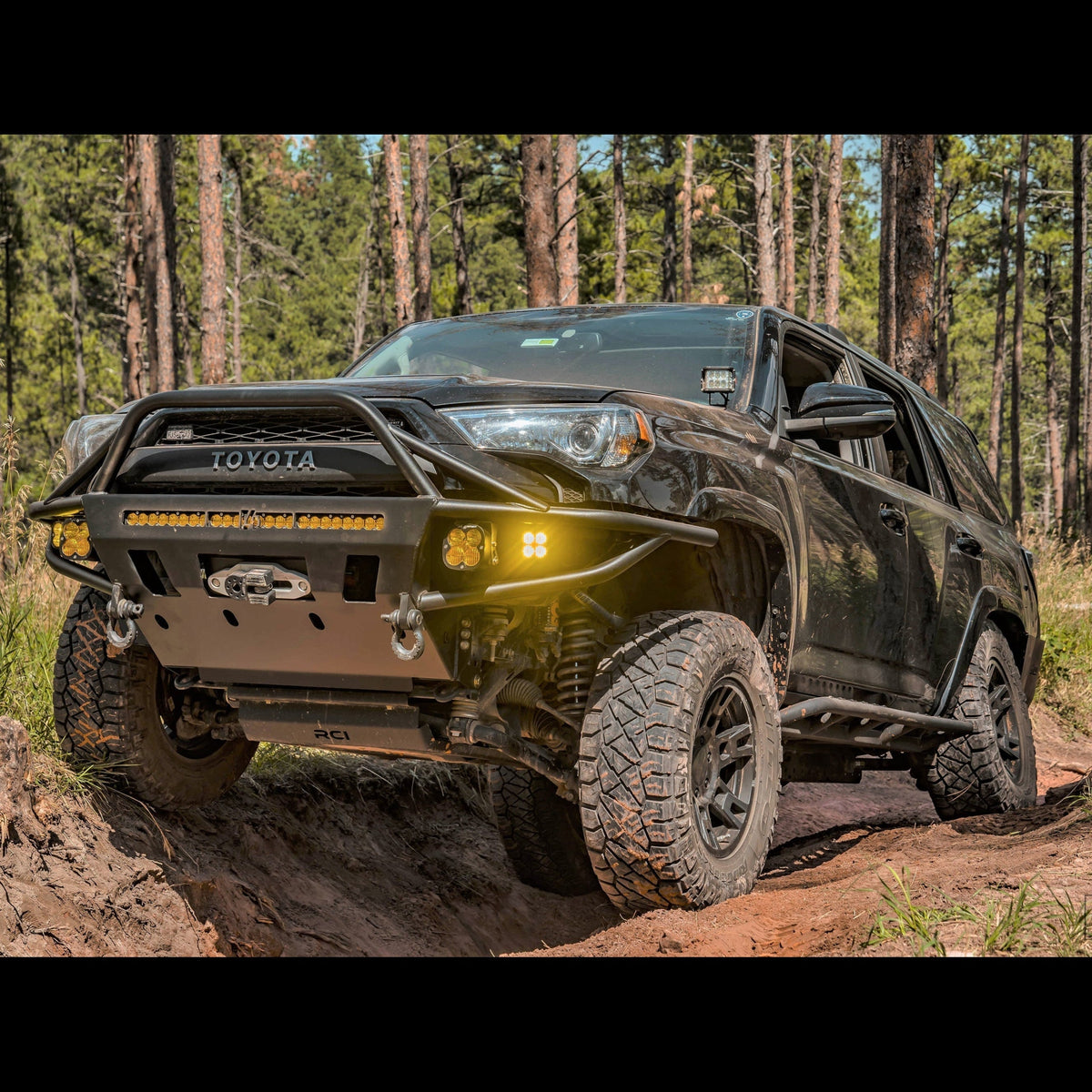 Black Toyota 4Runner spanning a dirt crevasse and equipped with the Hybrid tube/plate bumper manufactured by C4 Fabrication in Sturgis, SD.