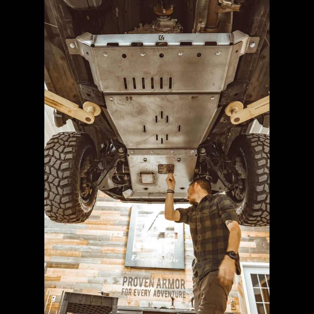 View from underneath and behind as the oil drain access panel is removed from the C4 full skid plates set for the 5th Generation 4Runner.