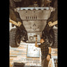 View from underneath and behind as the oil drain access panel is removed from the C4 full skid plates set for the 5th Generation 4Runner.